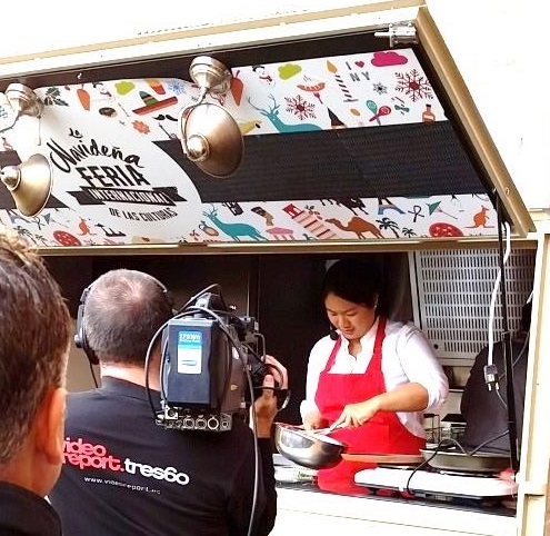 Consul Susana Mendiola demonstrates how to make lumpia in front of a camera.